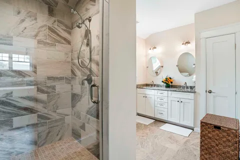 a bathroom with a granite countertop sink a mirror and shower