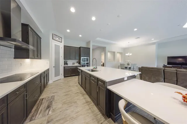 a large kitchen with a large counter top a sink stainless steel appliances and cabinets