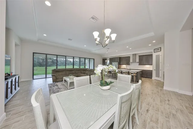 a view of a dining room and livingroom with furniture wooden floor a chandelier