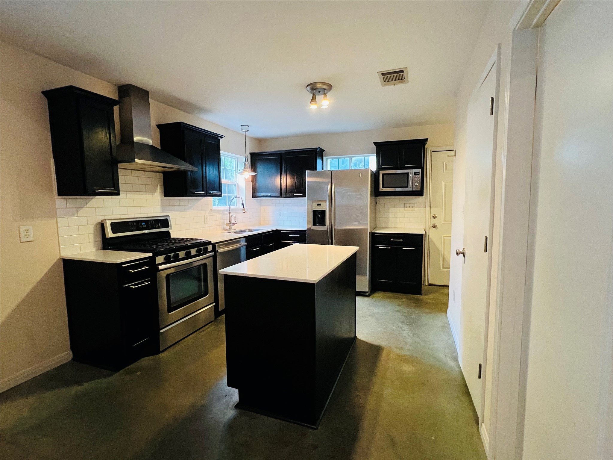 2409 Santa Rosa Street Austin, TX 78702 - Photo 4 of 27 Polished concrete floors and dark cabinetry define this modern kitchen with a central island.