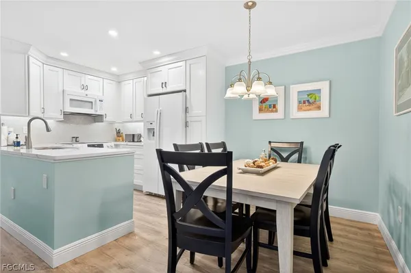 a kitchen with a dining table chairs and white cabinets