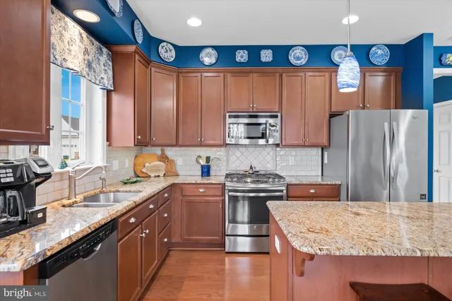 a kitchen with stainless steel appliances granite countertop a sink stove refrigerator and microwave