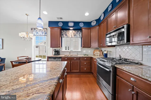 a kitchen with stainless steel appliances granite countertop wooden cabinets a stove top oven a sink and dishwasher