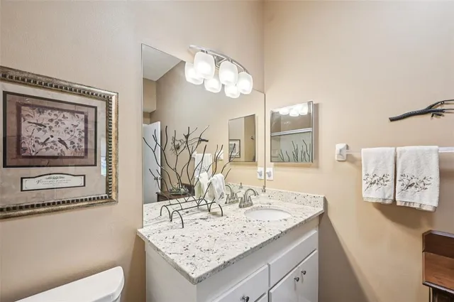 a bathroom with a granite countertop sink a toilet and a mirror