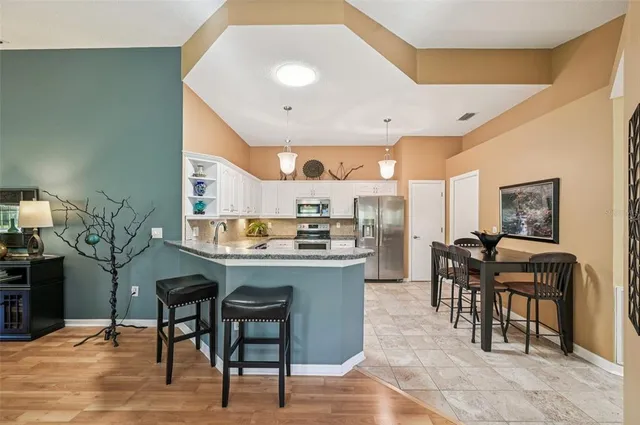 a kitchen with stainless steel appliances granite countertop a table chairs sink and cabinets