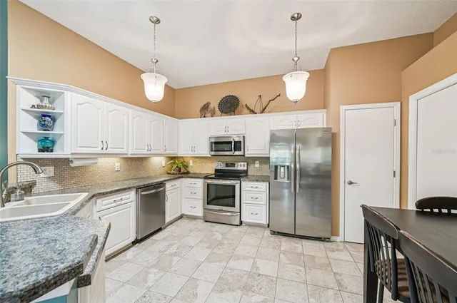 a kitchen with stainless steel appliances granite countertop a sink a stove and a refrigerator