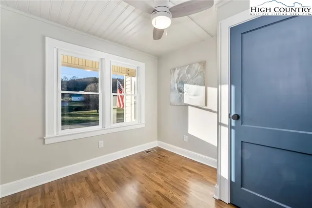 an empty room with wooden floor fan and windows