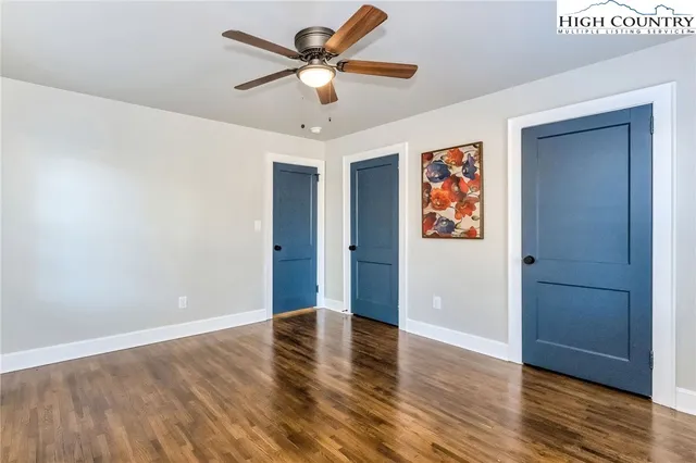 an empty room with wooden floor and ceiling fan