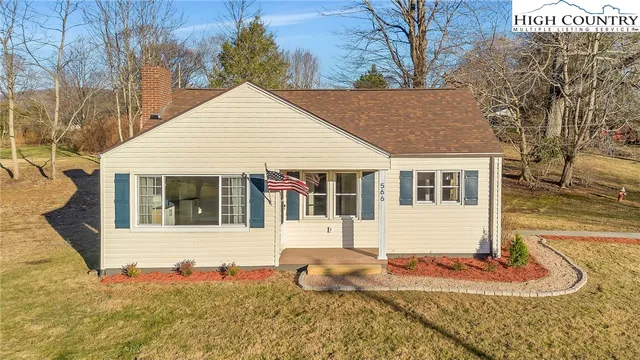 a view of a white house with large windows next to a yard