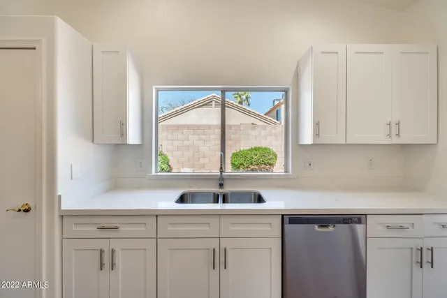 a kitchen with stainless steel appliances granite countertop white cabinets a sink and a large window