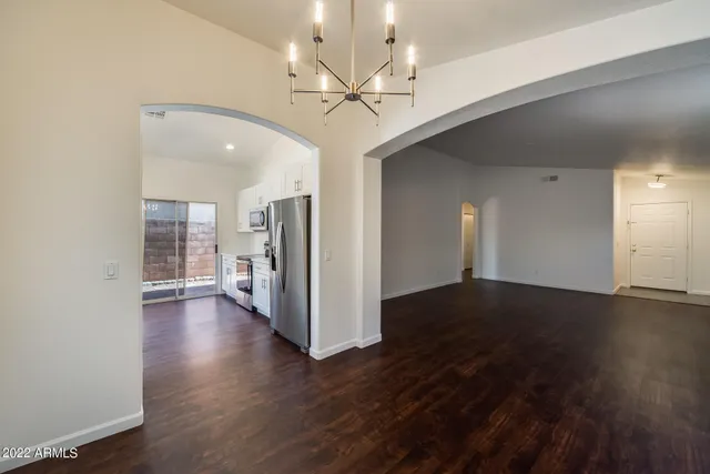 an empty room with wooden floor ceiling fan and windows