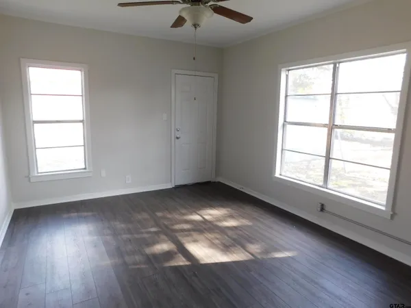 an empty room with wooden floor and windows