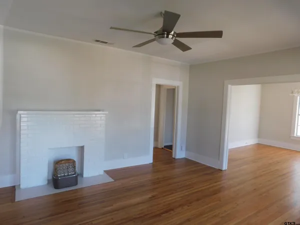 a view of empty room with wooden floor and fireplace