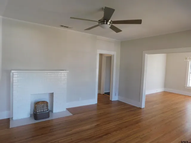 a view of empty room with wooden floor and fireplace