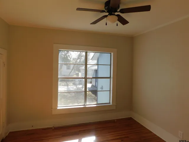 a view of an empty room with wooden floor and a window