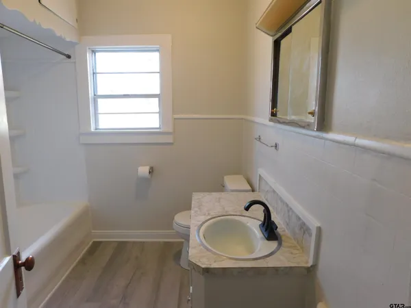 a bathroom with a toilet sink a window and mirror