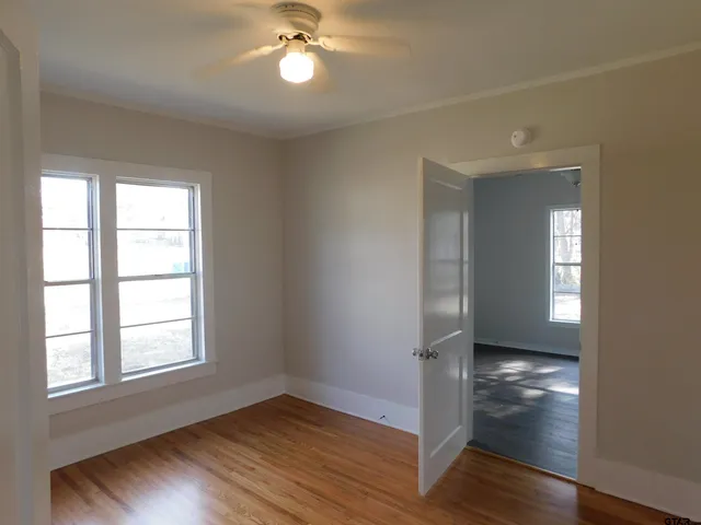 a view of empty room with wooden floor and fan