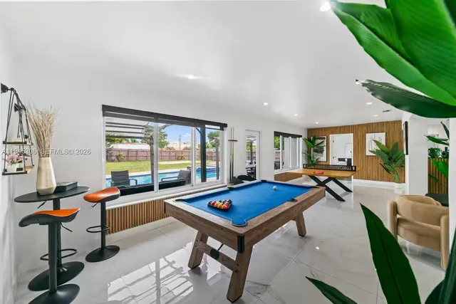 a living room with furniture pool table and a large window