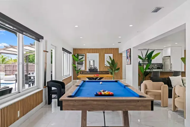 a living room with furniture pool table and large windows