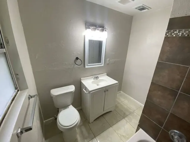 a white toilet sitting next to a bathroom sink and a mirror