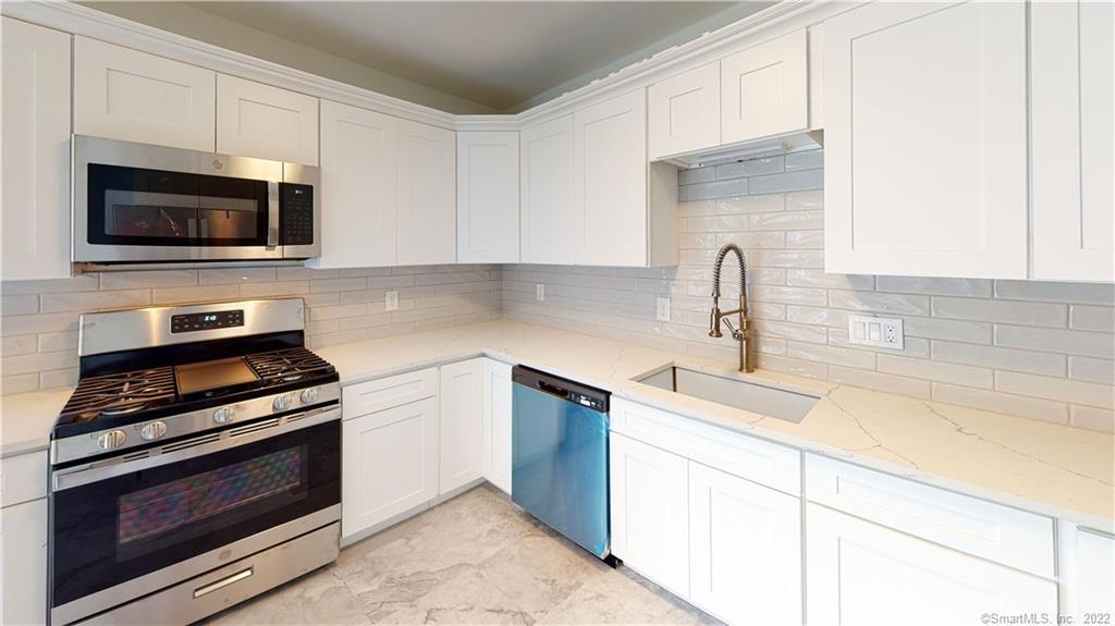 Renovated Kitchen with new stainless steel appliances, quartz counter tops, subway tile backsplash and new cabinetry.