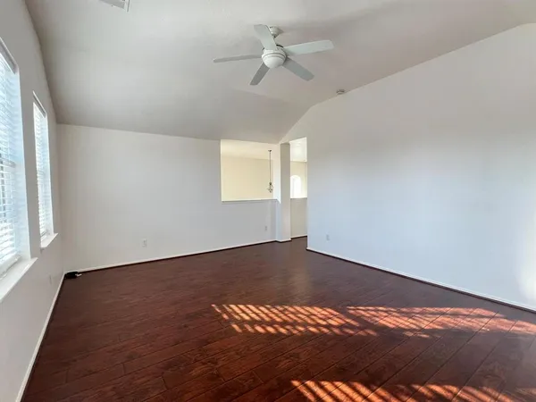 a view of an empty room with a window and wooden floor
