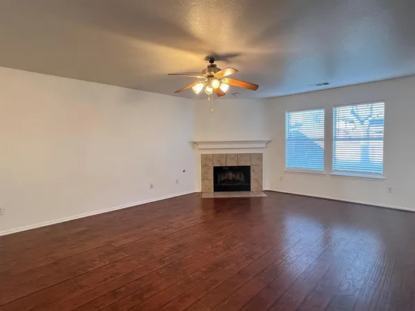a view of empty room with wooden floor fan and window