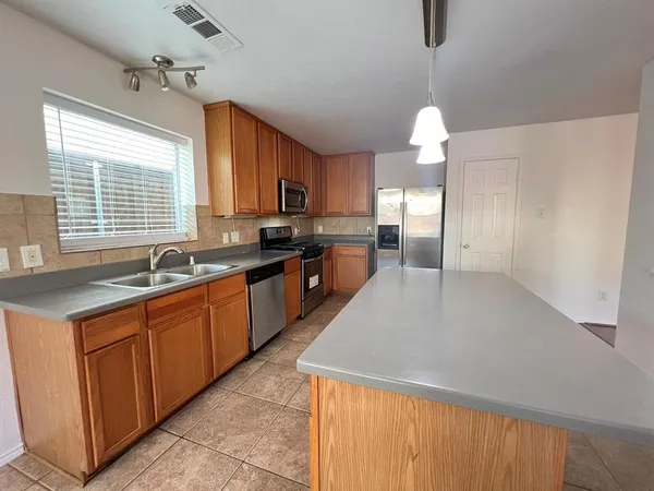 a large kitchen with kitchen island granite countertop a sink a counter top space and stainless steel appliances