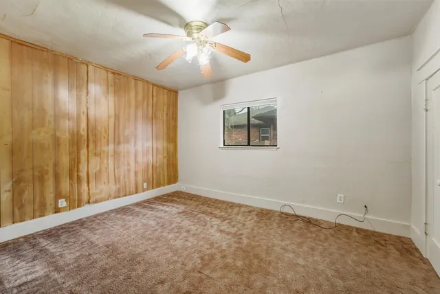 an empty room with windows and fan