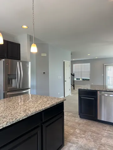 a kitchen with kitchen island granite countertop a stove cabinets and refrigerator