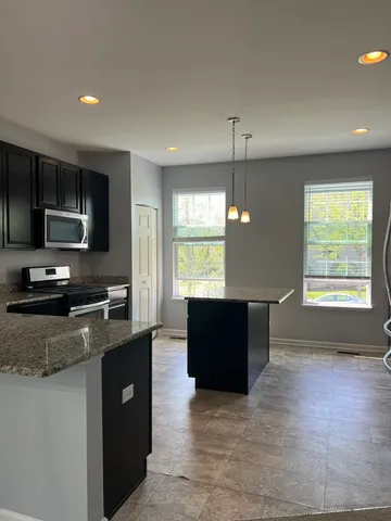 a kitchen with stainless steel appliances granite countertop a refrigerator a sink a stove a microwave and wooden cabinets