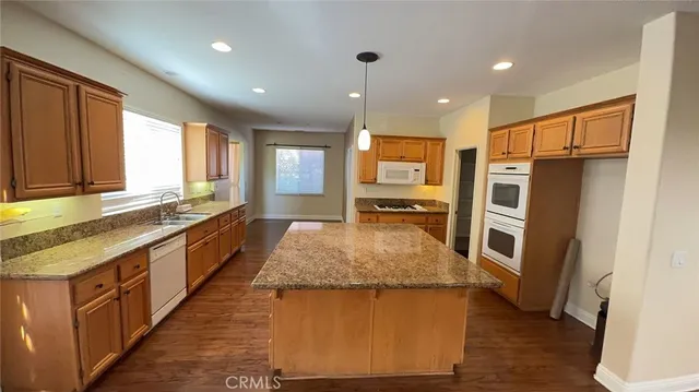 a large kitchen with kitchen island granite countertop wooden cabinets a sink and a refrigerator