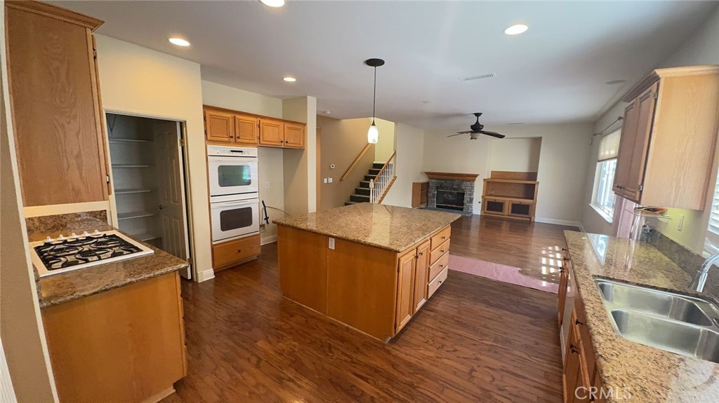 38265 Birch Court Murrieta, CA 92562 - Photo 10 of 46 a kitchen with stainless steel appliances kitchen island granite countertop a stove a refrigerator a oven and a dining table with wooden floor