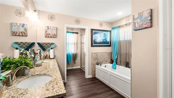 a bathroom with a granite countertop tub sink and mirror