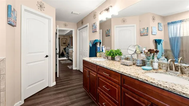 a bathroom with a granite countertop double vanity sink and a mirror