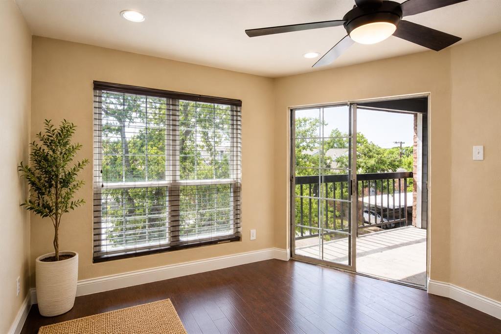 18333 Roehampton Drive, Unit 1036 Dallas, TX 75252 - Photo 3 of 12 Spacious room featuring wood-finish flooring, a large window with blinds, and a sliding glass door opening to an outdoor balcony