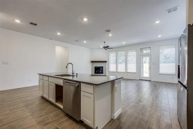 a view of a kitchen counter top space with stainless steel appliances granite countertop wooden floor and a window