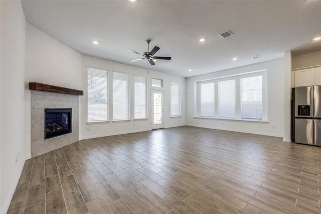 an empty room with wooden floor fireplace and windows