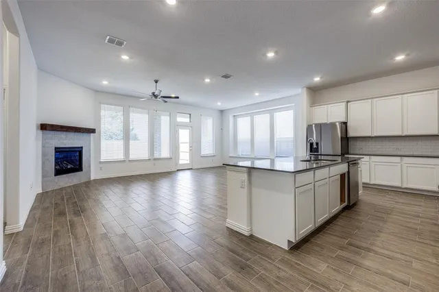 a large kitchen with stainless steel appliances granite countertop a large counter top a stove and a wooden floors
