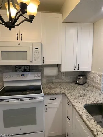 a kitchen with granite countertop a sink a stove and cabinets