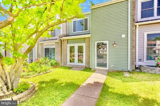 a view of a house with a small yard plants and large tree