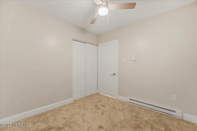 an empty room with a ceiling fan and carpet