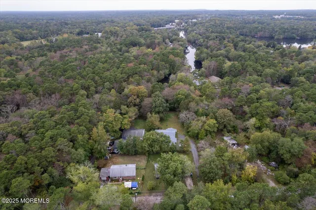 an aerial view of residential house with outdoor space and trees all around