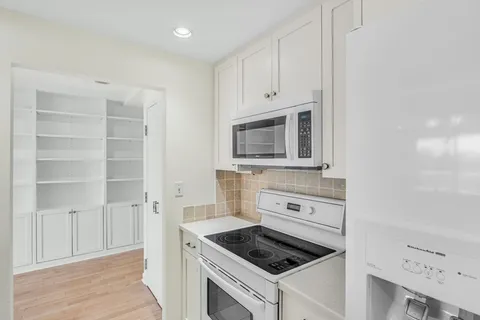 a kitchen with cabinets appliances and a wooden floor
