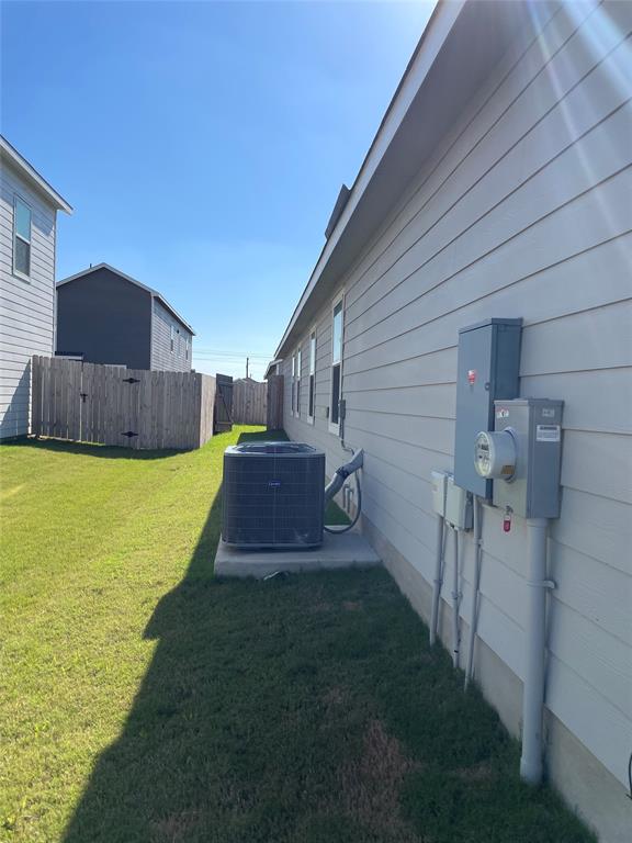 212 Marty Allen Loop Jarrell, TX 76537 - Photo 11 of 13 A tidy grassy lawn runs alongside the clean horizontal siding under a bright blue sky.