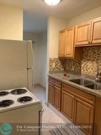 120 Northeast 10th Avenue, Unit 1 Hallandale Beach, FL 33009 - Photo 16 of 18 a kitchen with granite countertop a sink stove and refrigerator