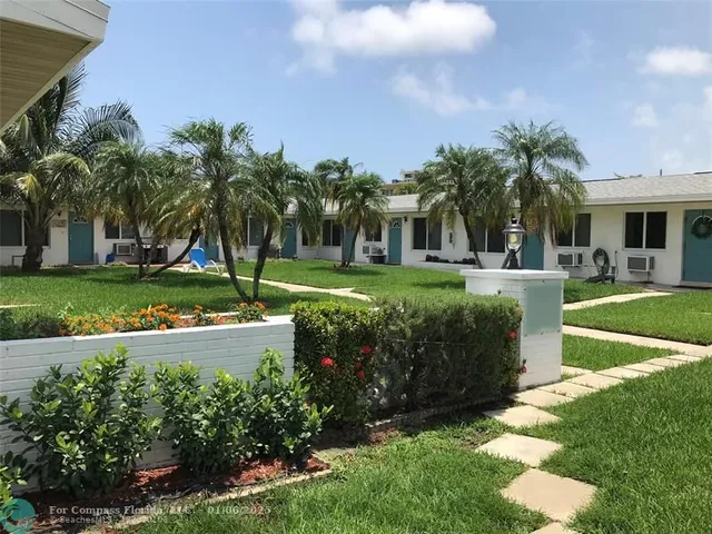 a front view of a house with a yard and potted plants