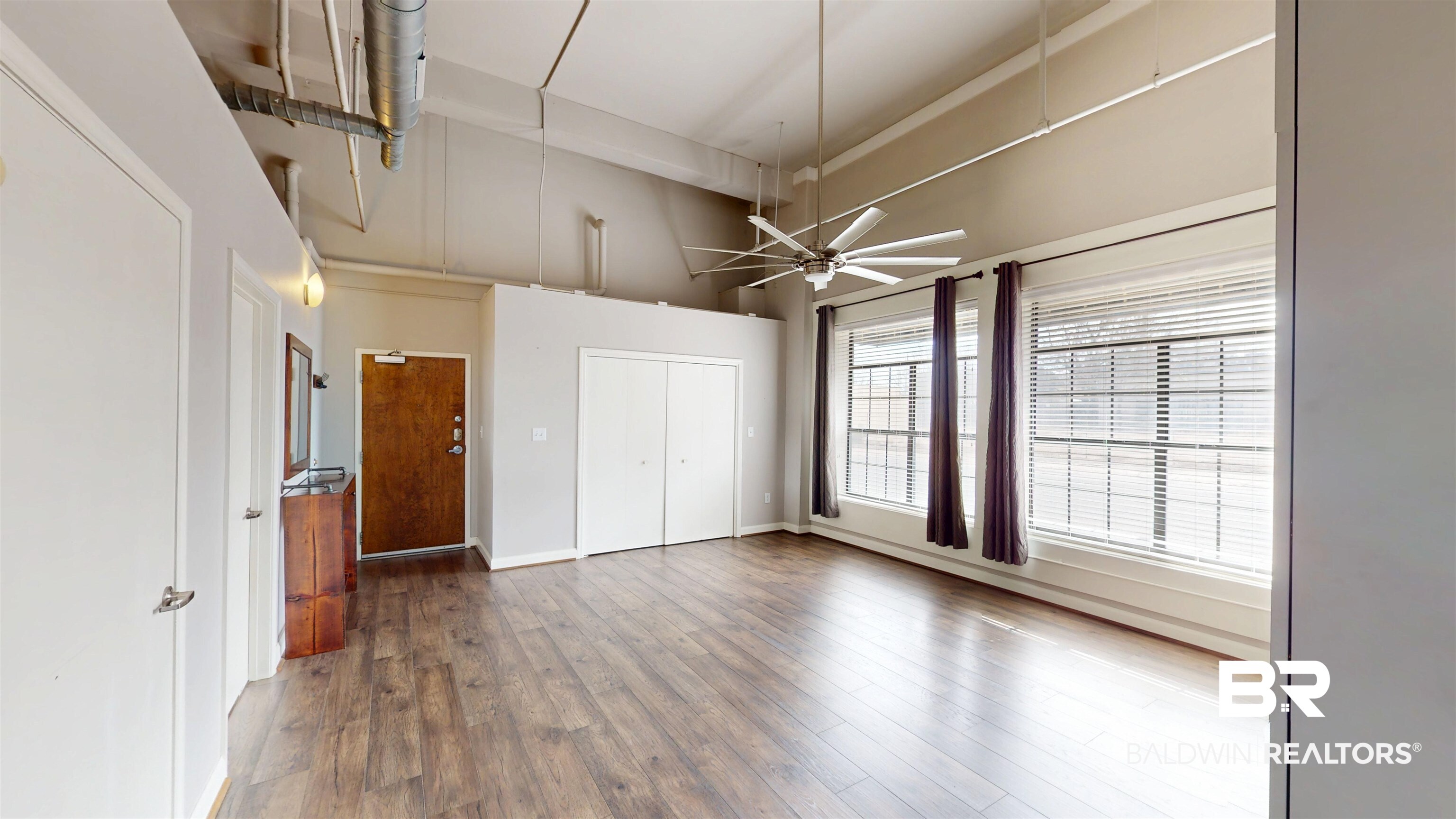 308 St Louis Street, Unit 101 Mobile, AL 36602 - Photo 26 of 30 Unfurnished bedroom featuring hardwood / wood-style floors, ceiling fan, a towering ceiling, and a closet