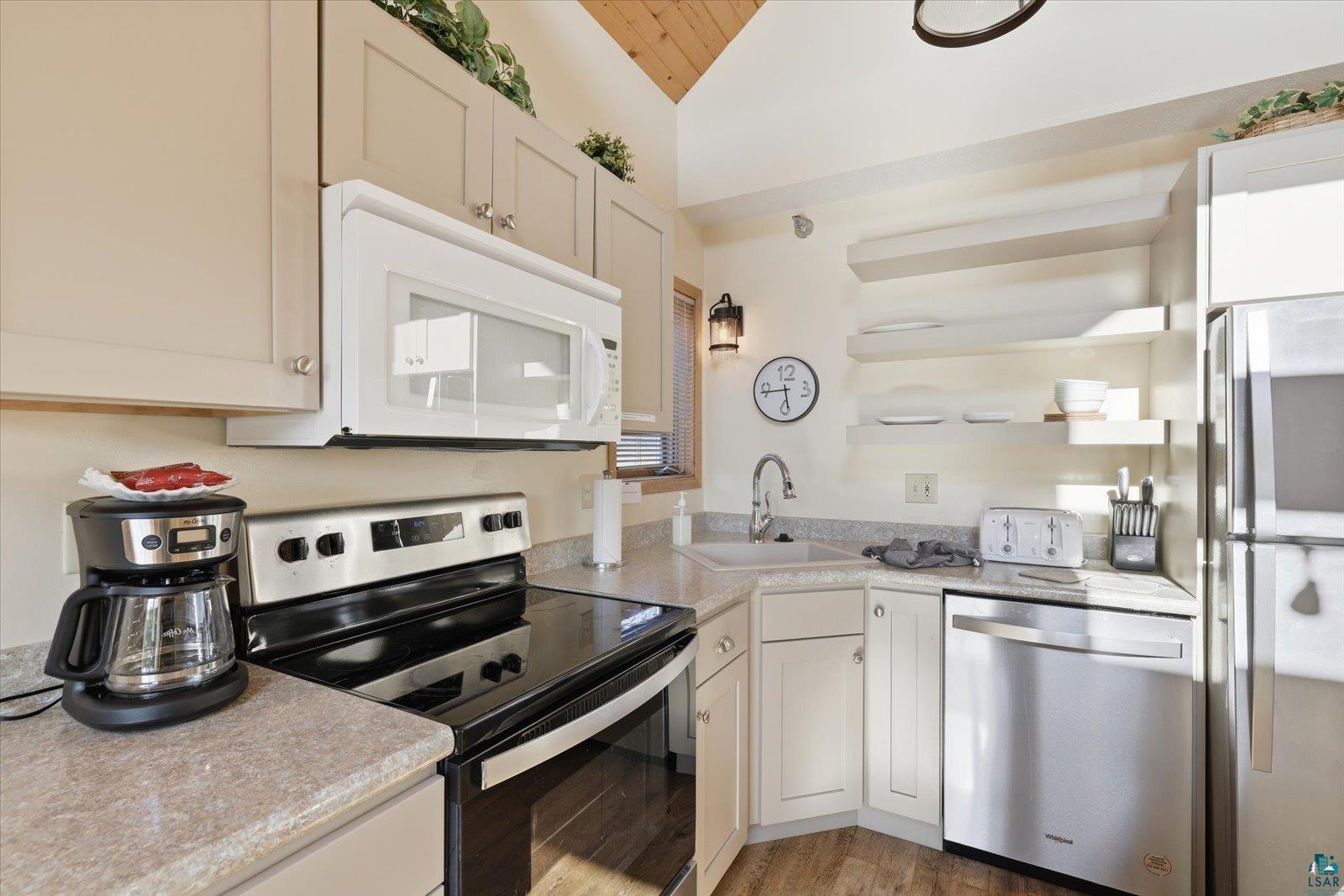 6266 Giants Ridge Road Biwabik, MN 55705 - Photo 8 of 29 Compact kitchen featuring stainless steel appliances, light-toned cabinetry, light countertops, a built-in microwave, and wood-finish flooring