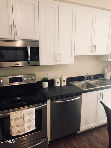 a kitchen with stainless steel appliances granite countertop a stove a microwave and white cabinets